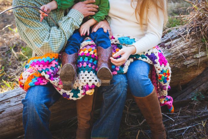 Parents cuddle a child sitting in their lap.