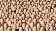 A crowd of people holding up John Malkovich masks to their faces
