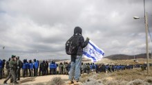 A settler holds an Israeli flag outside the West Bank outpost of Amona