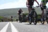 Riders on the road with a mountain in the background