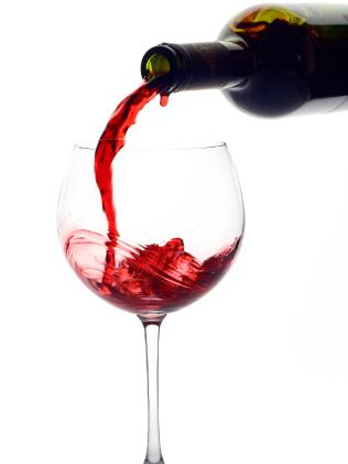 A picture of red wine being poured in a glass cup