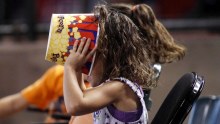 A young fan makes sure her popcorn is finished during a sporting event