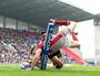 Joe Burgess of Wigan Warriors goes over for the opening try under pressure from Jesse Raimen of Cronulla at DW Stadium