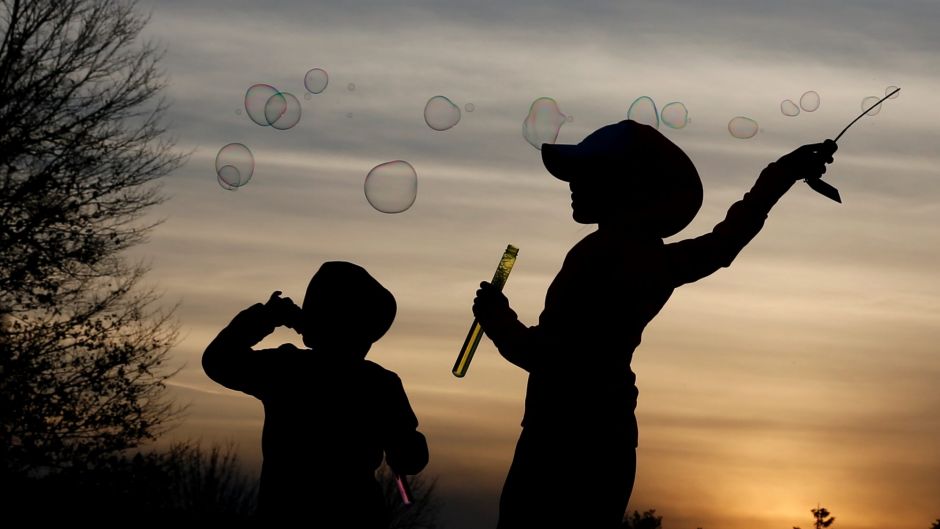 Children make soap bubbles at sunset in Chicago, Sunday, Feb. 19, 2017. 