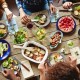 A group of people sit at a wooden table sharing food.