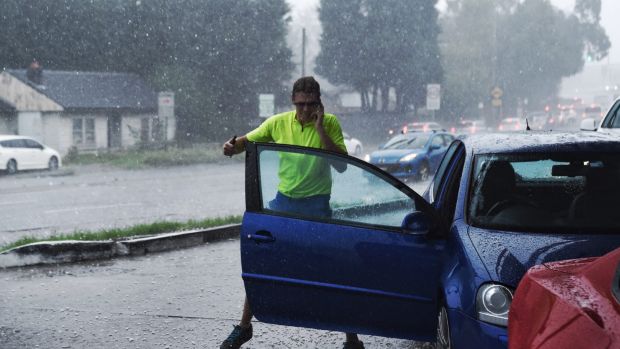 A man rushes from his car during a strong hail storm in Hornsby. Photo Nick Moir 18 feb 2017