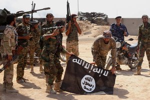 In this Tuesday, Oct . 7, 2014 file photo, Iraqi security forces hold a flag of the Islamic State group they captured during an operation outside Amirli, some 105 miles (170 kilometers) north of Baghdad, Iraq.