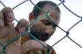 An unidentified Afghan man leans against a chainlink fence of a refugee camp after arriving with other asylum seekers on ...