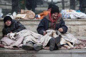 BUCHAREST, ROMANIA - FEBRUARY 07: Two homeless men sit with their dogs in central Bucharest on February 7, 2017 in ...