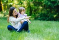 Woman sitting cross legged with toddler daughter in park