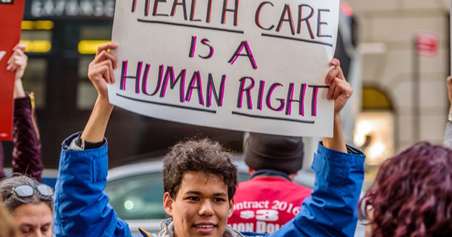 A young man holds up a sign at a recent rally against the repeal of the ACA