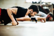 Close-up shot of a muay thai boxing athlete doing push-ups in a gym.