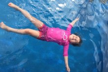 A child floats on her back in a pool.