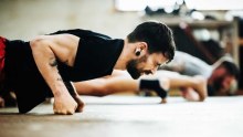 Close-up shot of a muay thai boxing athlete doing push-ups in a gym.