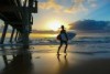 Surfer silhouetted against sunrise at the beach