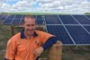 Electrician Michael Betts stands in front of solar panels on a Queensland farm.