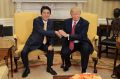 U.S. President Donald Trump, right, shakes hands with Shinzo Abe, Japan's prime minter, while posing for photographs ...