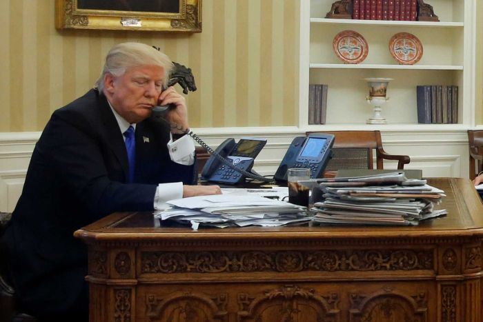 US President Donald Trump (L), seated at his desk in the White House speaks with Australian Prime Minister Malcolm Turnbull.