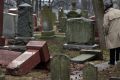 People walk through toppled graves at Chesed Shel Emeth Cemetery in University City, Missouri.