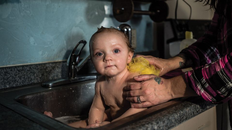 Child being bathed in a sink.