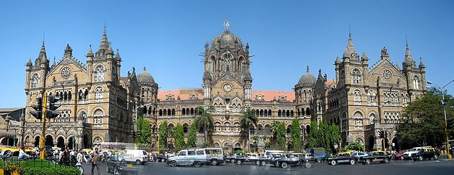 A brown building with clock towers, domes and pyramidal tops. Also a busiest railway station in India.[284] A wide street in front of it