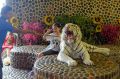 A tourist poses for a photo with a tiger that is kept in check by a handler's stick, at the Tiger Temple.