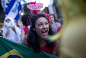 A reveler wearing a crown with a sign that reads in Portuguese: "Come back Dilma" shouts slogans against Brazil's President Michel Temer, during the "Out Temer" carnival street party in Rio de Janeiro, Brazil