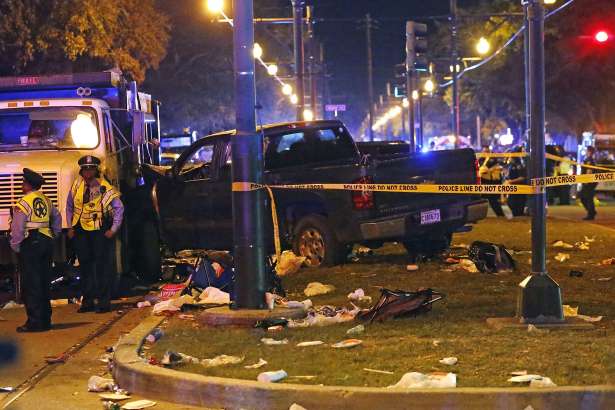 Police stand next to a pickup truck that slammed into a crowd and other vehicles, causing multiple injuries, coming to a stop against a dump truck, during the Krewe of Endymion parade in New Orleans, Saturday, Feb. 25, 2017. (AP Photo/Gerald Herbert)