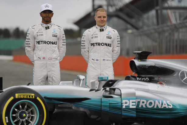 Los pilotos de Mercedes, Lewis Hamilton, izquierda, y Valtteri Bottas posan con el vehículo de la escudería para la temporada de 2017 de la Fórmula Uno el jueves, 23 de febrero de 2017, en Towcester, Inglaterra.