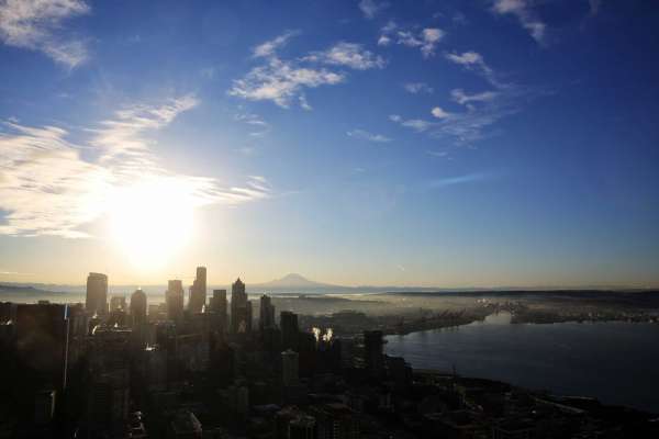 The sun rises over Mount Rainier and the Seattle skyline early Friday morning as seen from the Space Needle.