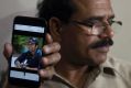 A man shows a picture of Alok Madasani, as his father Jaganmohan Reddy talks to the media in Hyderabad, India.