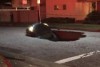 The bonnet of a car sticks out from the pavement on a California road, after falling in a sinkhole.