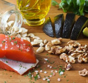 Salmon seasoned with salt, cashews, walnuts, sliced avocado, and olive oil, garnished with parsley.