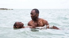 Mahershala Ali holds Alex R Hibbert in the water as he teaches the child to swim in a scene from Moonlight.