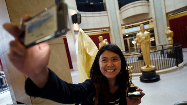 Australian tourist Susanne Wong from Brisbane takes a selfle with a tiny Oscar statue at the Hollywood and Highland Center in Los Angeles Friday, as final preparations were underway for Sunday's 89th Academy Awards.