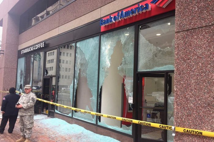 Security guards the front of a Bank of America and Starbucks outlet which have smashed windows.
