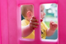 Blurred picture of prison baby through a pink toy with hand in focus.