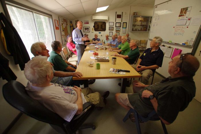 John Day addresses a group of men sitting around a table.