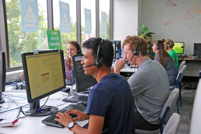 Young people at computers with headsets on making calls to voters