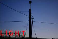 An unlit street light is shown in front of the Seattle City Light building with its signature red neon sign in SODO.
