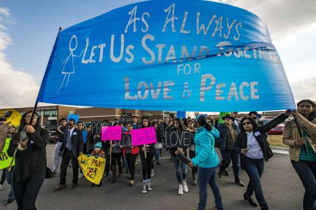 Hundreds of people march for peace on Sunday, Feb. 26, 2017, around the Ball Conference Center in Olathe, Kan., before starting a prayer vigil in response to the deadly shooting Wednesday. Adam Purinton was arrested hours after the attack and accused of shooting two Indian immigrants and a third man at a bar, in what some believe was a hate crime. (Allison Long/The Kansas City Star via AP)