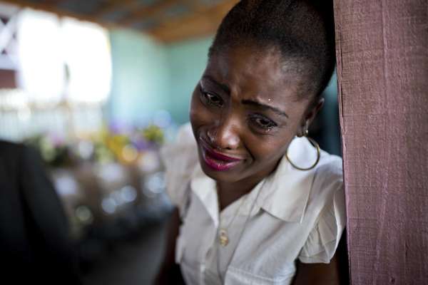 In this Tuesday, Feb. 21, 2017 photo, a woman cries near the coffin containing the body of a relative who died at the country's largest prison in Port-au-Prince, Haiti. Relatives wailed in grief or stared stoically as flowers were placed on 20 caskets at a mass funeral for the latest group of inmates who died miserably in Haiti's largest prison, most without ever having been convicted of any crime.