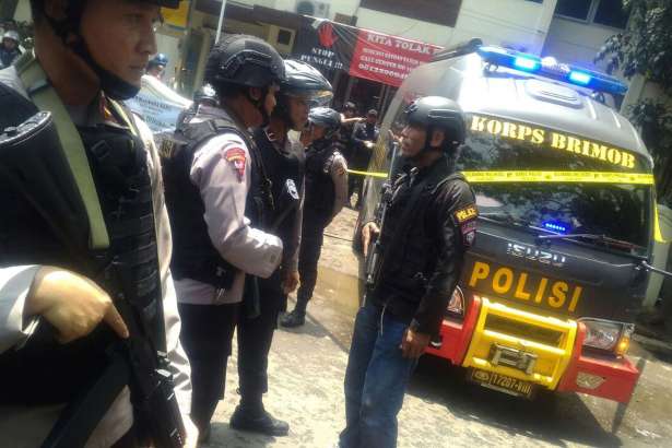 Police officers stand guard outside the municipal building after a stand off between a suspected militant and anti-terror police in Bandung, West Java, Indonesia, Monday, Feb. 27, 2017. Indonesian police say they shot the suspected militant in the West Java capital after his bomb exploded in a vacant lot and he fled into the municipal building and set it alight.