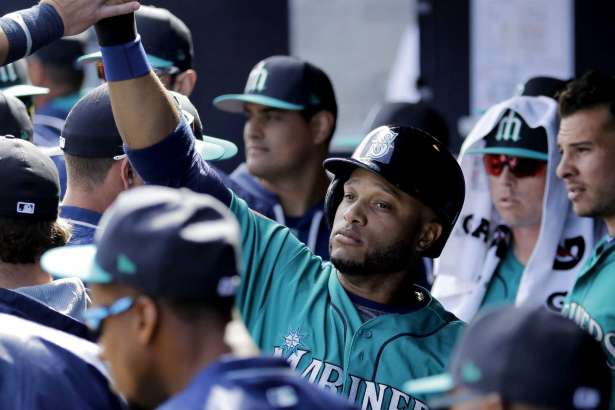 Seattle Mariners' Robinson Cano celebrates in the dugout after scoring when Tyler O'Neill was walked with the bases loaded during the third inning of a spring training baseball game against the San Diego Padres, Sunday, Feb. 26, 2017, in Peoria, Ariz.