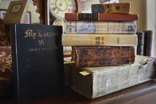 In this Jan. 19, 2017 photo, a collection of books is displayed in the home of Mike Vincent, a retired teacher, who has been collecting books since he got "Tom Sawyer" in fifth grade,  in Albuquerque, N.M. This stack includes a theological book from 1634, a Civil War era Bible, with inscribed personal notes about a family's experience during the war, "Lolita" by Vladimir Nabokov, John Steinbeck's "Grapes of Wrath", "Through the Looking-Glass" by Louis Carroll, a Mickey Mouse book from 1940 and "My Battle" by Adolphe Hitler.  (Marla Brose /The Albuquerque Journal via AP)