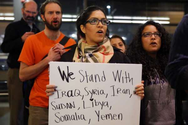 A woman holds up a sign as the last group of protesters makes their final stand in the departures terminal around 2:00 a.m Sunday. More than 1,000 people gather at Seattle-Tacoma International Airport, Saturday, January 28 to protest President Trump's immigration ban.  President Trump signed an executive order Friday that bars citizens from Iraq, Syria, Iran, Libya, Somalia, Sudan and Yemen from entering the U.S. for the next 90 days and suspends the admission of all refugees for 120 days.