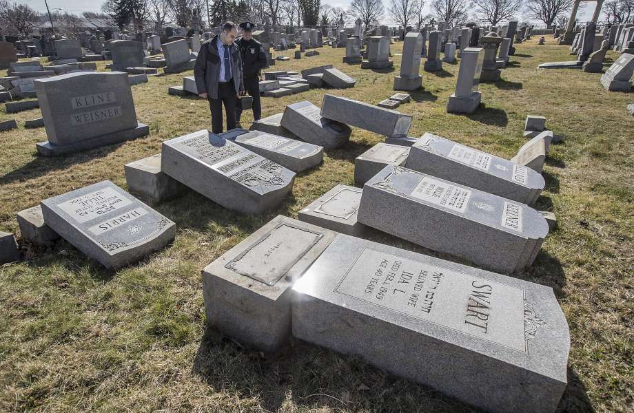 Northeast Philadelphia Police Det. Timothy McIntyre and another Philadelphia police officer look over tombstones that were vandalized in the Jewish Mount Carmel Cemetary Sunday, Feb. 26, 2017 in Philadelphia. A police spokeswoman said preliminary estimates are that 75 to 100 graves were damaged  The vandalism was discovered Sunday morning.    (Michael Bryant/The Philadelphia Inquirer via AP) Photo: Michael Bryant, Associated Press