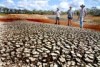 Three men stand on the bank of an almost dry dam