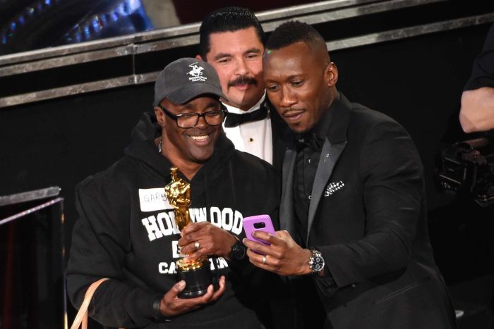 Mahershala Ali takes a selfie with a fan holding his Oscar