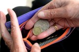 A woman's hand puts coins into a wallet.